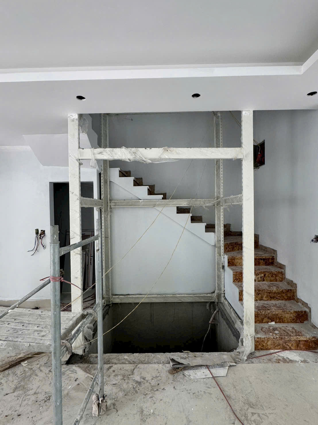 Thi công cầu thang đá trong nhà đang xây dựng với khung thang máy ở giữa